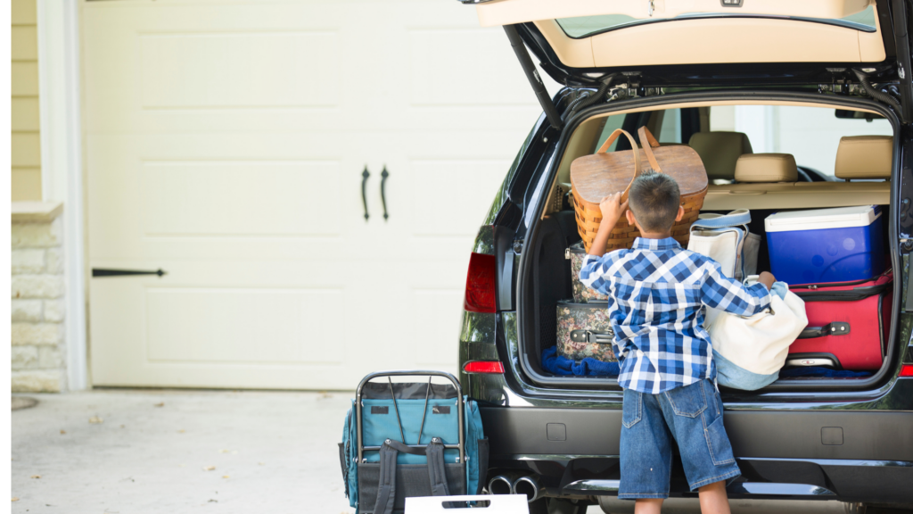 Little boy helping to pack luggage into a van for a family vacation